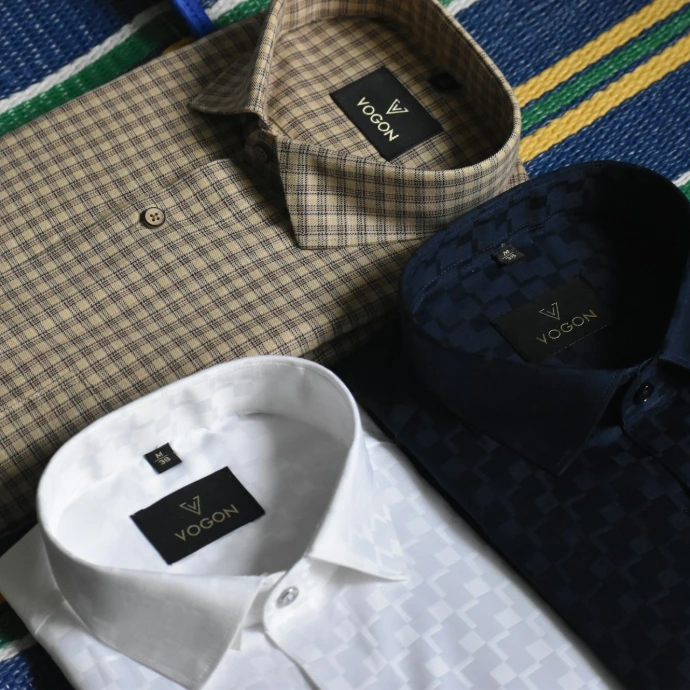 a variety of men's shirts laid out on a bed
